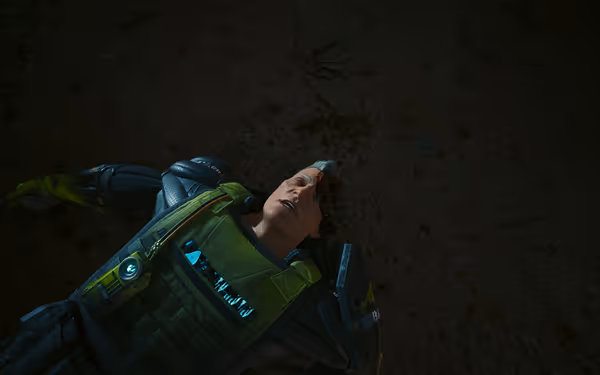 A man in green futuristic armor lies on the ground with head trauma visible.