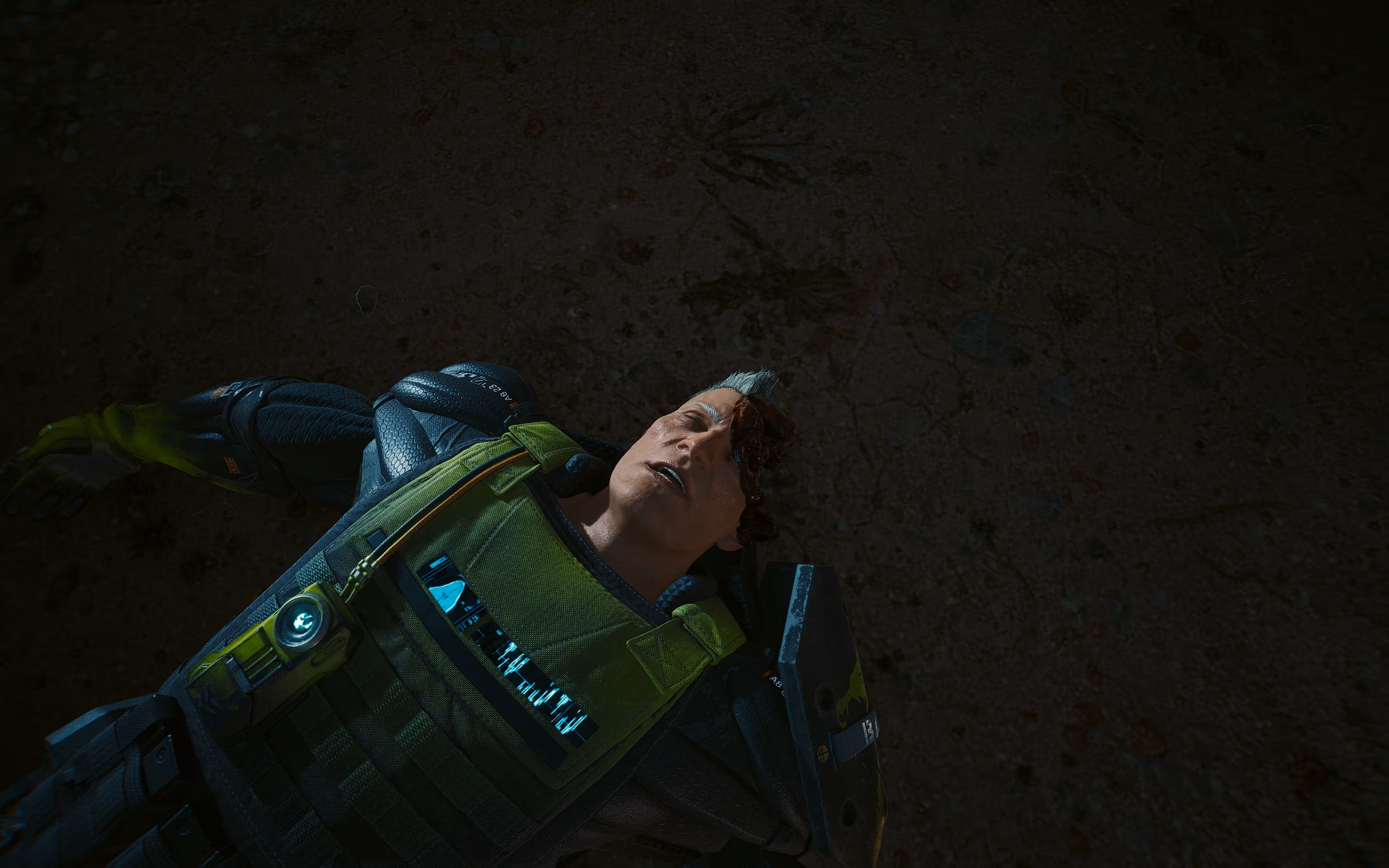 A man in green futuristic armor lies on the ground with head trauma visible.