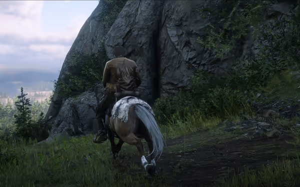 A rider ventures through a scenic mountain trail under a cloudy sky.