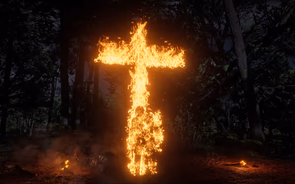 A burning male character stands in front of a burning cross at night in the forest.