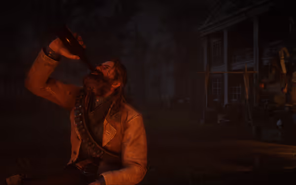 A bearded man drinks by firelight near an old house, surrounded by supplies and dark trees at night.