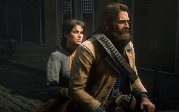 A rugged, bearded character in a coat sits in front, while a female character in a checkered dress sits behind him on a street in front of a building.