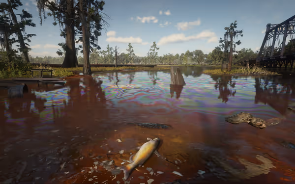 A daytime view of a serene swamp scene with a dead fish on the shore, a railroad bridge in the distance, and an oil slick marring the water's surface.
