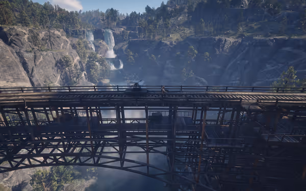 Bridge over canyon with waterfalls and trees in background.