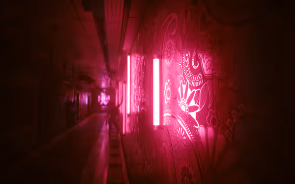 A dimly lit corridor with glowing pink lights and intricate floral wall designs