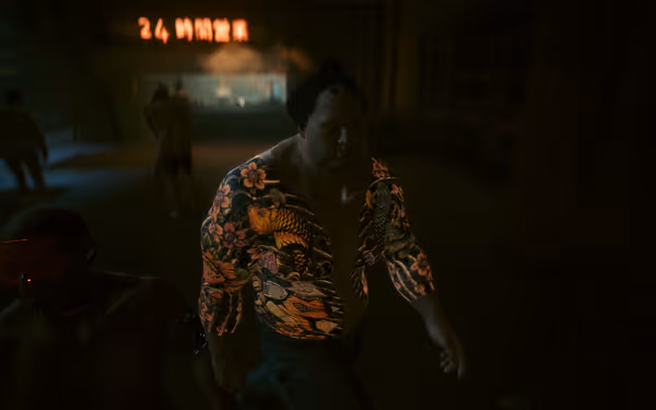 A muscular man with vibrant tattoos walks in a dimly lit urban environment.