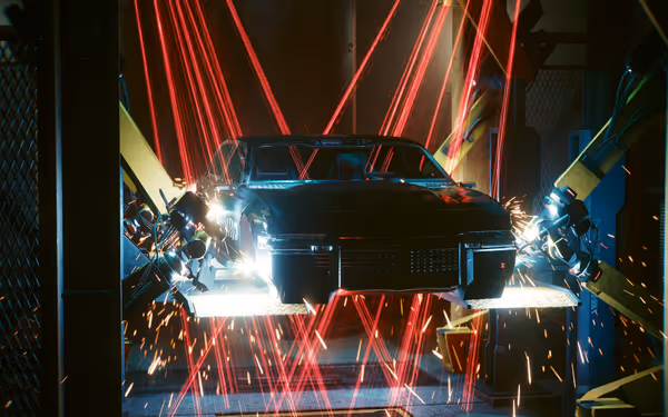 A black futuristic car is suspended in a workshop with robotic arms and lasers.