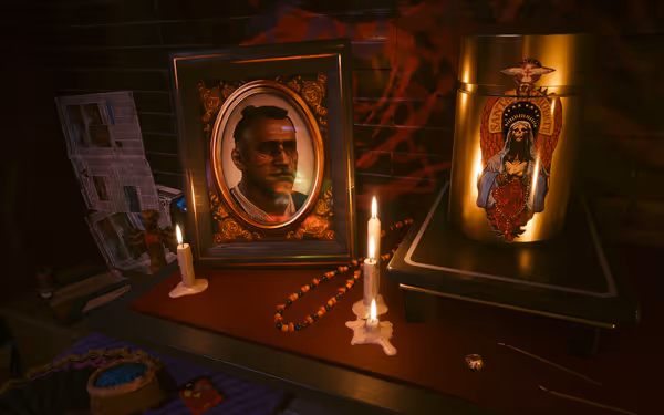 A framed portrait of a man with facial cracks, lit candles, beads, and an urn.