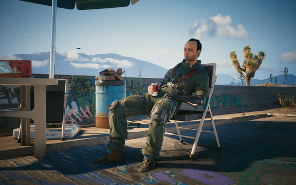 A man with a cybernetic arm sits in a chair holding a drink outside.