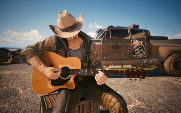 A man in a cowboy hat plays a worn guitar beside a rugged armored truck.
