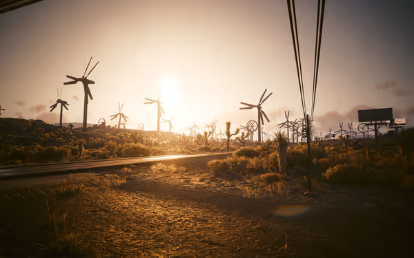 A dusty road stretches through a desert landscape filled with rusted wind turbines.