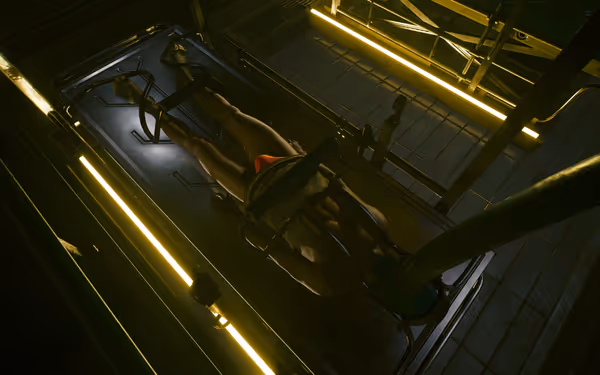 A restrained person lies on a metal table, connected to a machine by tubes.