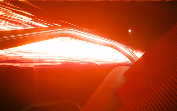 A blinding red energy beam shoots through a metallic tunnel with glowing reflections.
