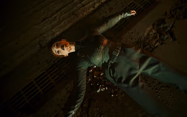 Woman lies dead on gritty floor with blood around mouth and chest wound.