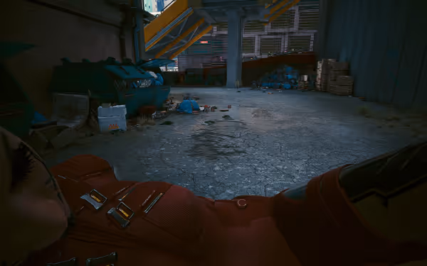 A body in a red suit is carried to a dumpster under a bridge.