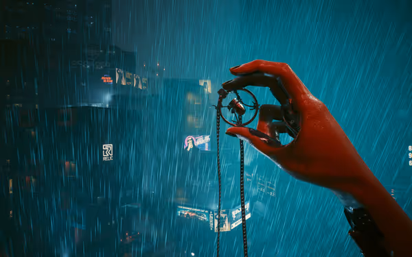A red cybernetic hand holds a bullet pendant in heavy rain above neon-lit buildings.