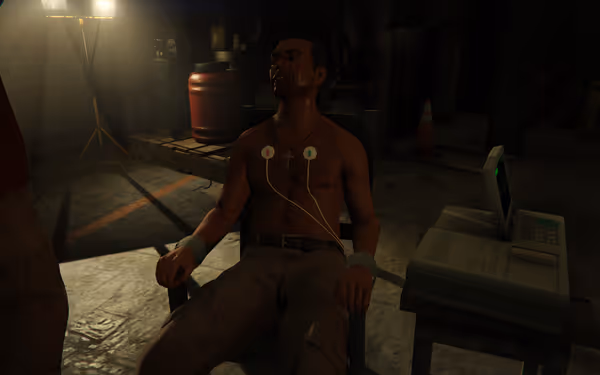 A shirtless, restrained man with medical pads on chest sits in a dimly lit room.