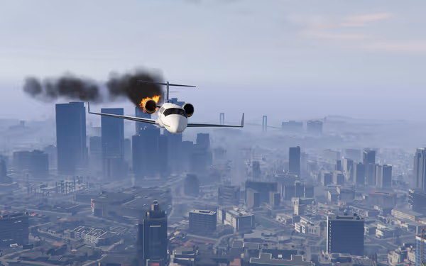 A jet flies over a city with one engine on fire, trailing black smoke.