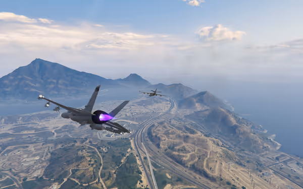 Two fighter jets are flying over mountainous terrain with a coastal view in the background.