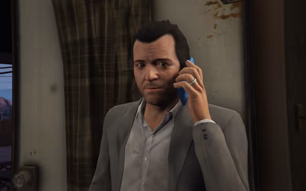 A man in a grey suit is talking to someone on a blue phone indoors.