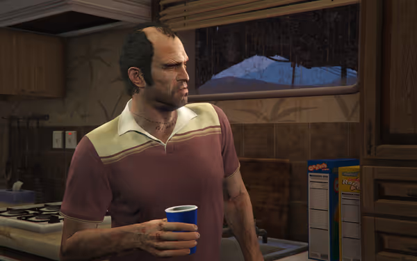 A man in a maroon polo stands in a kitchen holding a blue cup.