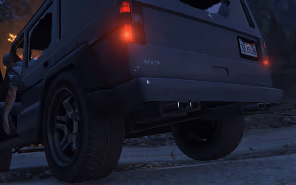 A person climbs into a black V12 SUV with broken window and license plate 20LKR638 near fire at night