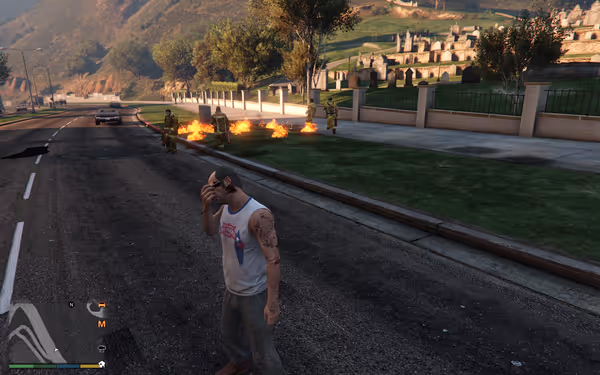 A man in a tank top with tattoos is near firefighters and a fire on the road.