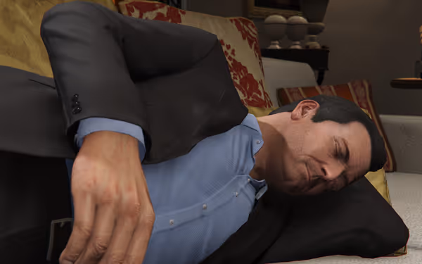 A man in a suit lies resting peacefully on a couch indoors.