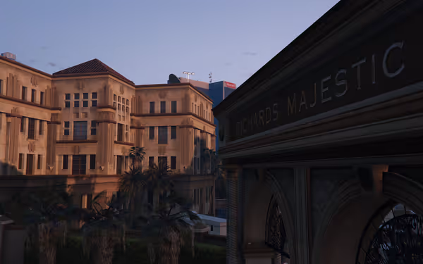 Large tan buildings with palm trees and a sign reading “Richards Majestic” at dusk.