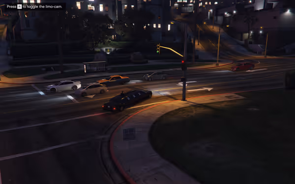 Cars wait at a night-time intersection with a black limousine in the foreground.