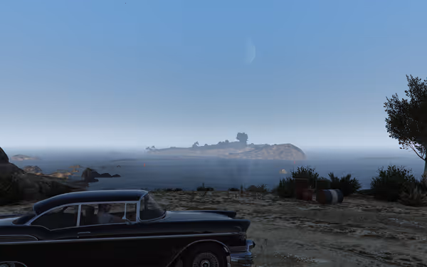 A classic black car is parked near the shore, facing a distant island under blue sky.