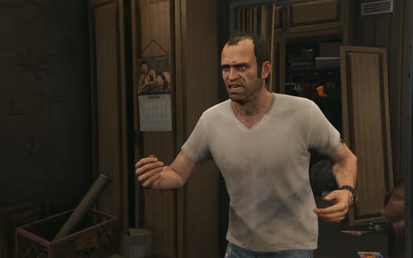 A man in a dirty white t-shirt stands in a cluttered room with open closet.