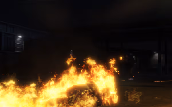 Person engulfed in large flames on ground at night, another figure stands further back.