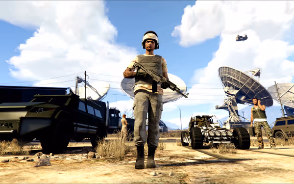 A soldier with a rifle stands near military vehicles and satellite dishes.