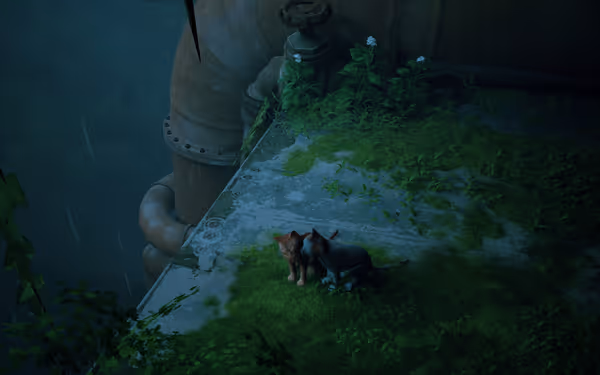 Two small cats sit together on a mossy ledge beside large rusty pipes.