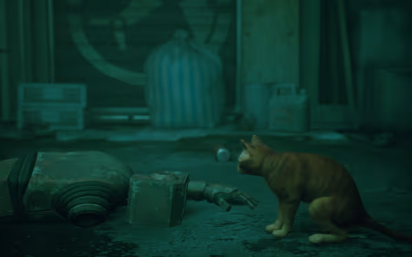 An orange cat sits beside the broken arm of an old robot on a green floor.